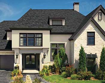 Front view of a generic-looking mid-class home with charcoal black GAF shingles on the roof